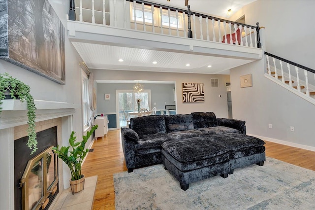 living room with light wood-type flooring, baseboards, stairway, and a tiled fireplace