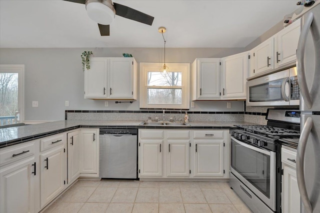 kitchen with light tile patterned floors, stainless steel appliances, a ceiling fan, white cabinetry, and a sink