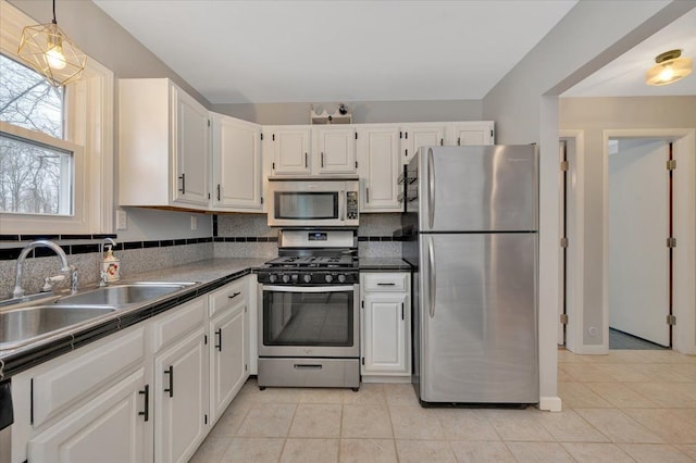 kitchen featuring light tile patterned floors, a sink, stainless steel appliances, white cabinetry, and backsplash