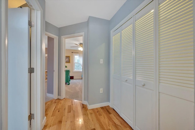 hall featuring light wood-style flooring and baseboards