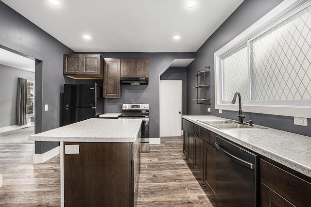 kitchen featuring under cabinet range hood, a kitchen island, a sink, light countertops, and black appliances