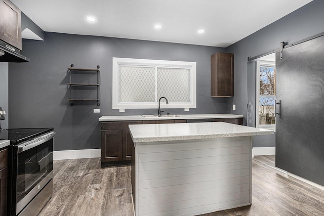 kitchen with stainless steel electric range oven, dark brown cabinets, and a sink