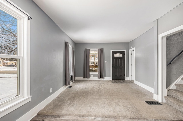 entrance foyer with carpet, stairs, visible vents, and baseboards