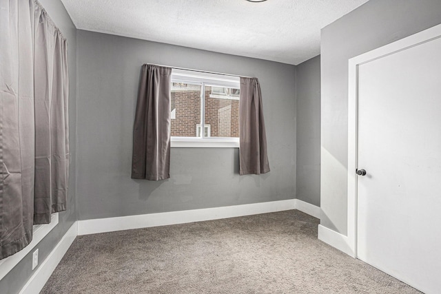 unfurnished bedroom with carpet, a textured ceiling, and baseboards