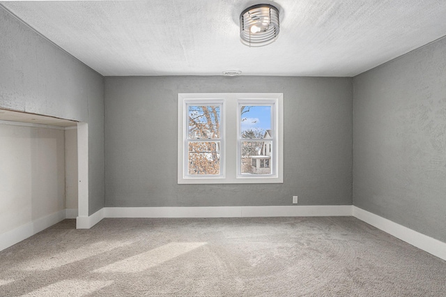 unfurnished bedroom featuring carpet, a textured ceiling, and a textured wall