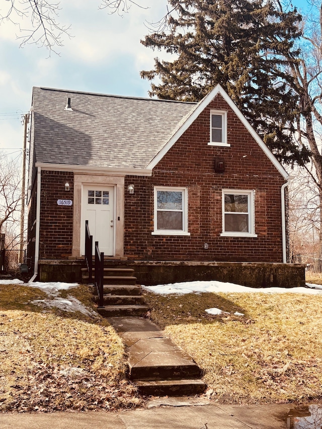 view of front of home with a shingled roof and brick siding