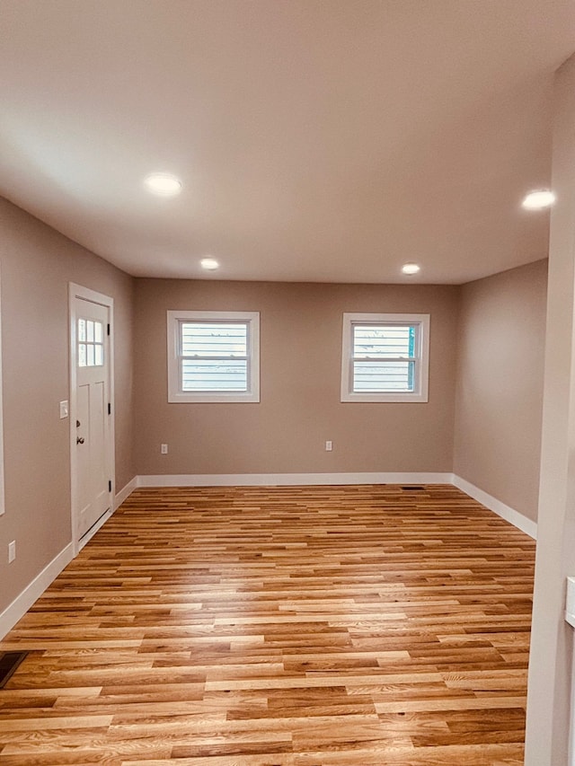 spare room with a healthy amount of sunlight, light wood finished floors, and baseboards