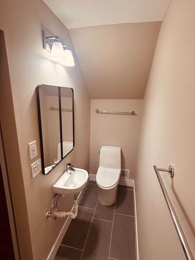 half bathroom with a sink, tile patterned flooring, toilet, and baseboards