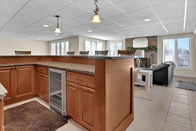 kitchen featuring a healthy amount of sunlight, wine cooler, open floor plan, and hanging light fixtures