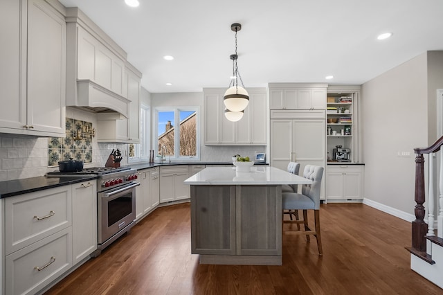 kitchen with decorative light fixtures, dark wood finished floors, a breakfast bar area, tasteful backsplash, and high quality appliances