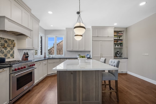 kitchen featuring dark wood-type flooring, high end appliances, a kitchen bar, and decorative backsplash