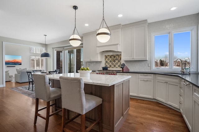 kitchen featuring a kitchen bar, decorative backsplash, dark wood finished floors, and a sink