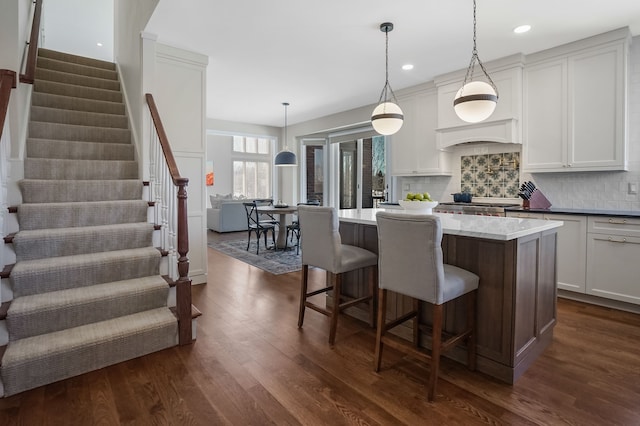 kitchen featuring tasteful backsplash, a center island, dark wood finished floors, and a breakfast bar