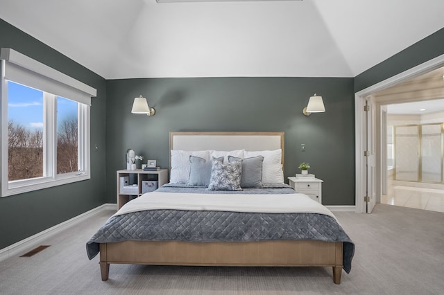 bedroom with carpet floors, visible vents, connected bathroom, vaulted ceiling, and baseboards