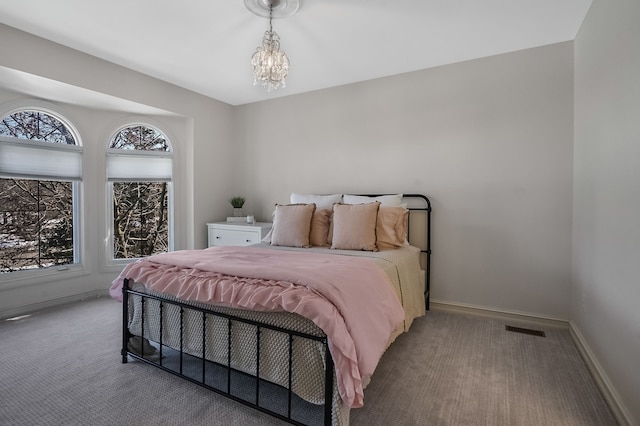 carpeted bedroom featuring a chandelier, visible vents, and baseboards