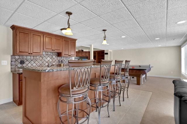 kitchen featuring baseboards, brown cabinetry, and decorative backsplash