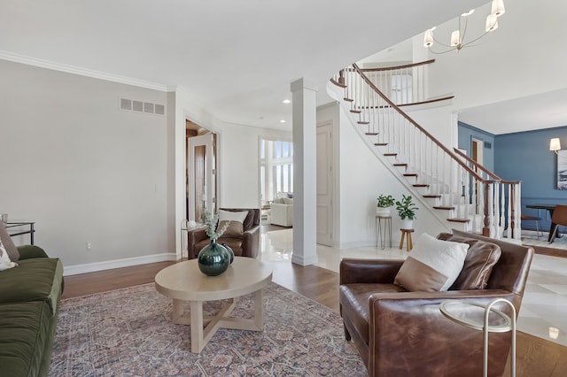 living room with decorative columns, visible vents, wood finished floors, baseboards, and stairs