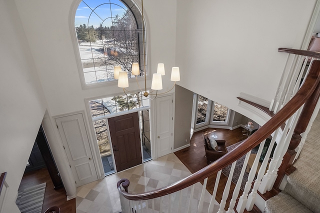 foyer entrance featuring stairs, tile patterned floors, a towering ceiling, and a notable chandelier