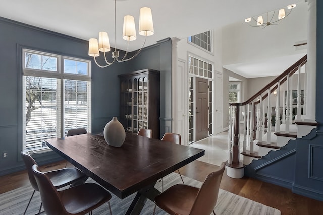 dining room featuring visible vents, stairway, wood finished floors, a high ceiling, and a notable chandelier