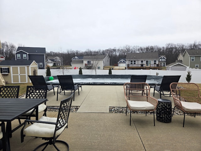 view of patio featuring outdoor dining area, a residential view, and a storage unit