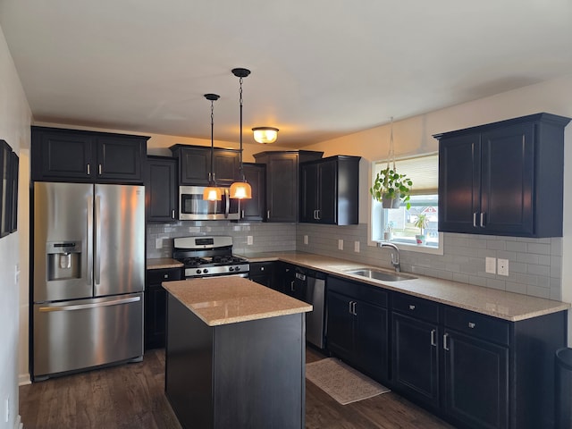 kitchen with a sink, a kitchen island, dark wood finished floors, stainless steel appliances, and decorative backsplash