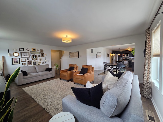 living area with visible vents, a healthy amount of sunlight, dark wood-type flooring, and baseboards