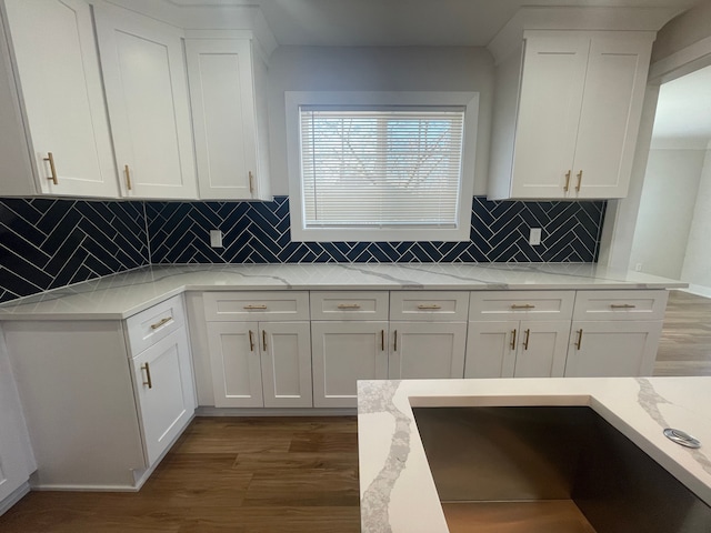 kitchen with wood finished floors, white cabinets, decorative backsplash, and light stone countertops