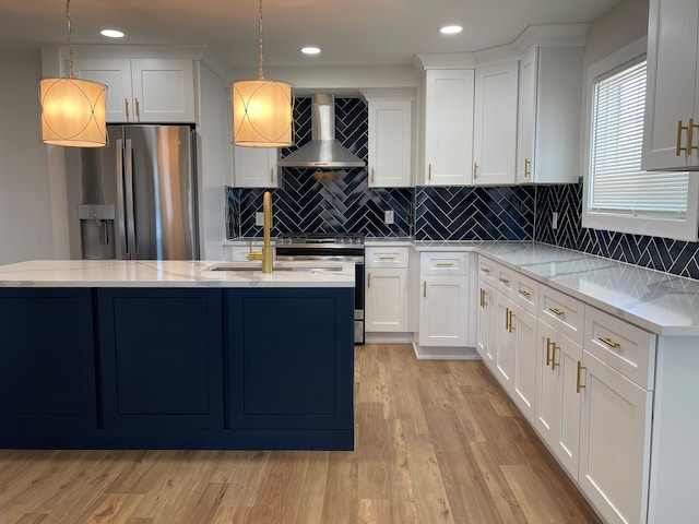 kitchen featuring wall chimney exhaust hood, white cabinetry, stainless steel appliances, and decorative light fixtures