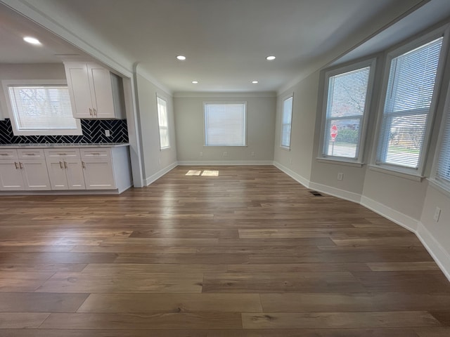 interior space with tasteful backsplash, dark wood-type flooring, dark countertops, and white cabinets