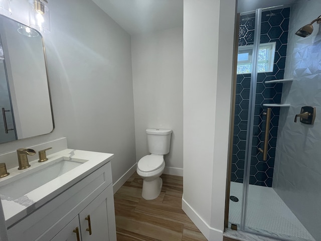 full bath with a stall shower, baseboards, toilet, wood finished floors, and vanity