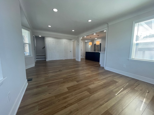 interior space with dark wood-style floors, stainless steel fridge, visible vents, and baseboards