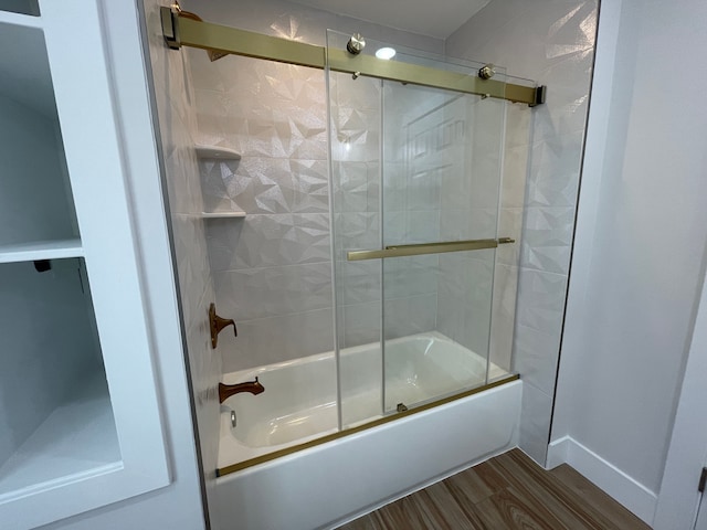 bathroom with enclosed tub / shower combo, baseboards, and wood finished floors