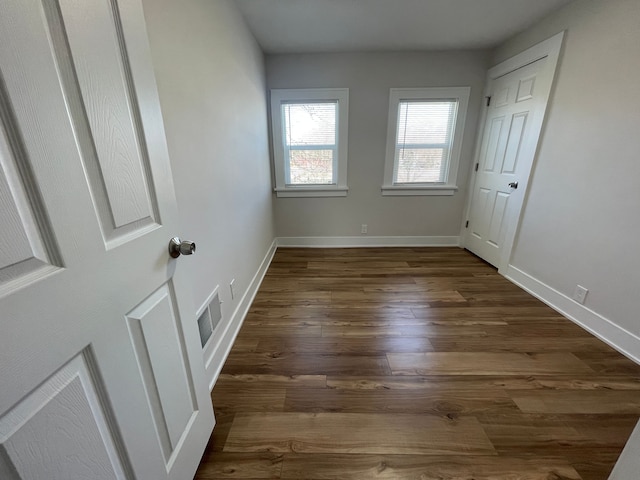 interior space featuring dark wood-style floors, visible vents, and baseboards