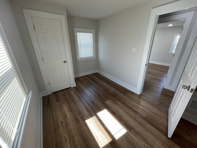 unfurnished bedroom with dark wood-type flooring and baseboards