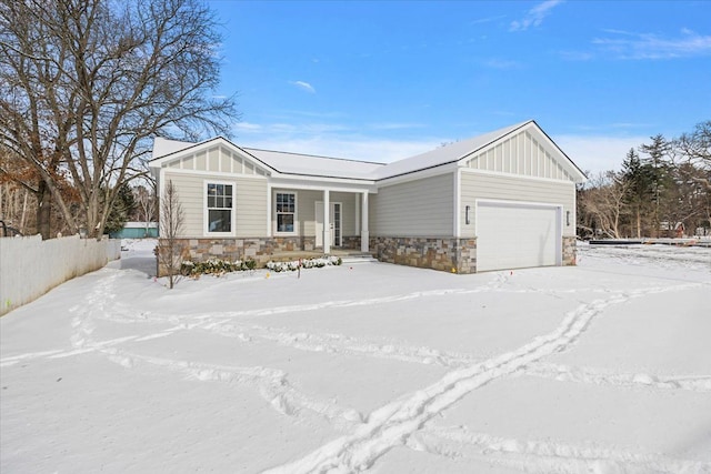 view of front of home with a garage, stone siding, fence, and board and batten siding