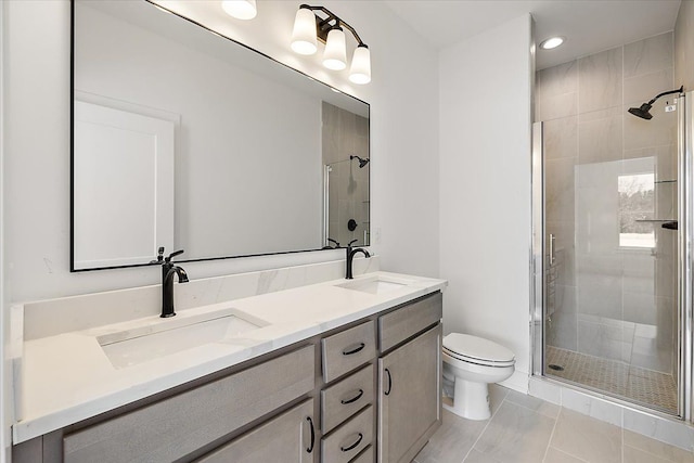 bathroom with double vanity, a stall shower, a sink, and toilet