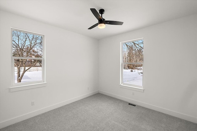 empty room featuring a ceiling fan, carpet flooring, visible vents, and baseboards