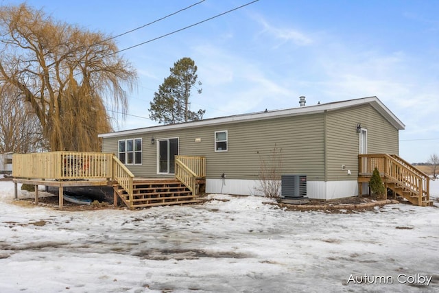 snow covered rear of property with stairs, a wooden deck, and central air condition unit