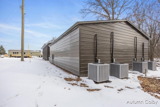 snow covered structure featuring central AC unit