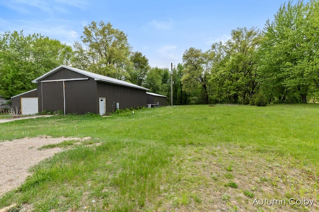 5443 Gravel Ridge Rd, Lakeview, MI 48850 - view of green lawn with a detached garage, an outbuilding, an outdoor structure, and view of wooded area