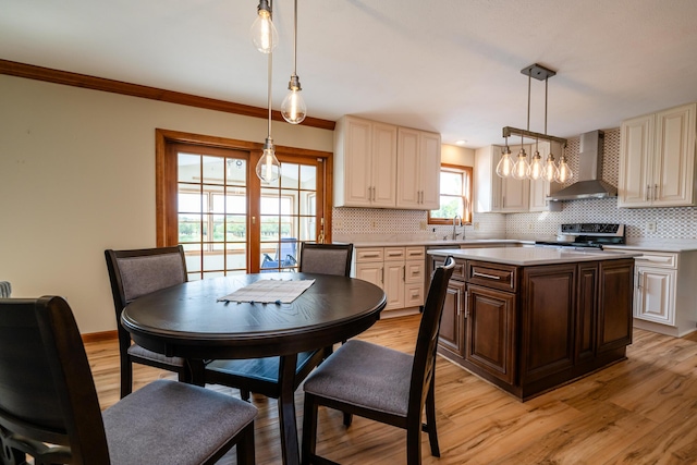 kitchen featuring a center island, pendant lighting, stainless steel stove, light countertops, and wall chimney exhaust hood