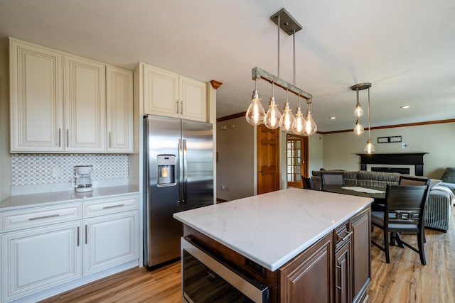 kitchen featuring dark brown cabinetry, light wood-style floors, open floor plan, stainless steel refrigerator with ice dispenser, and decorative light fixtures