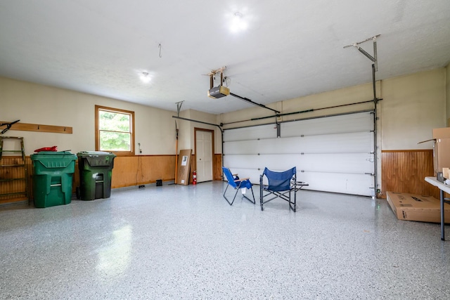 garage with wainscoting, wooden walls, and a garage door opener