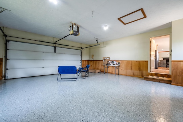 garage featuring a wainscoted wall, wooden walls, and a garage door opener