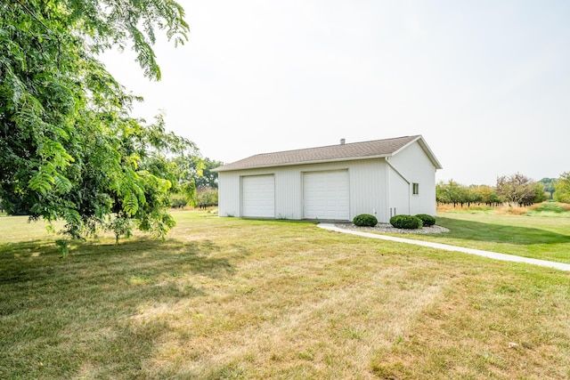 view of side of property featuring a garage, a lawn, and an outdoor structure