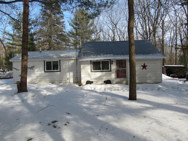 snow covered property with metal roof and an attached garage