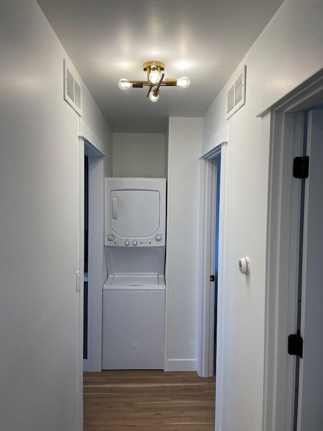 laundry room featuring dark wood-style floors, laundry area, visible vents, and stacked washer / drying machine