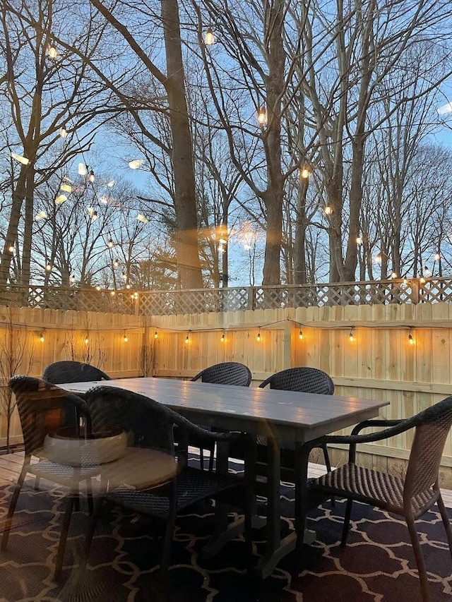 patio terrace at dusk featuring fence and outdoor dining space