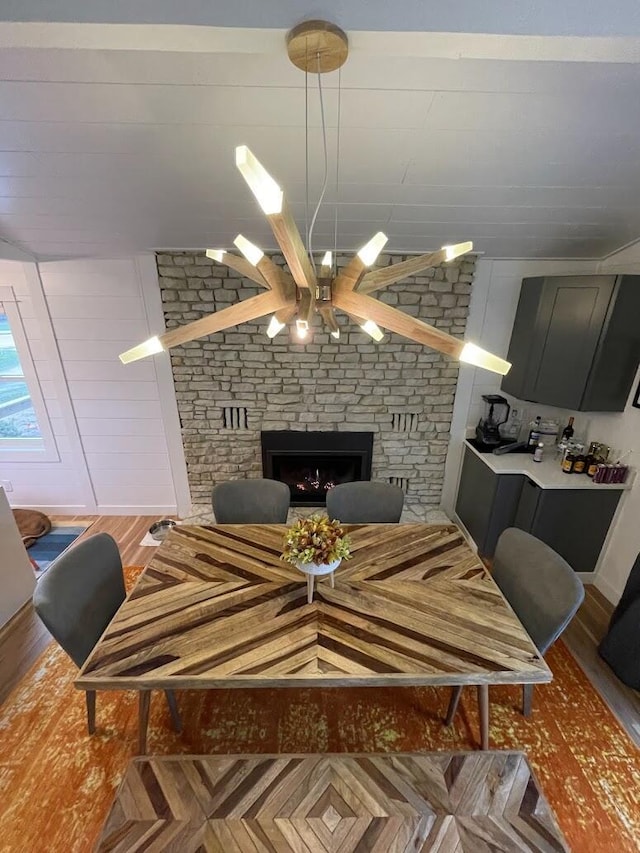 dining room featuring a stone fireplace and wood finished floors