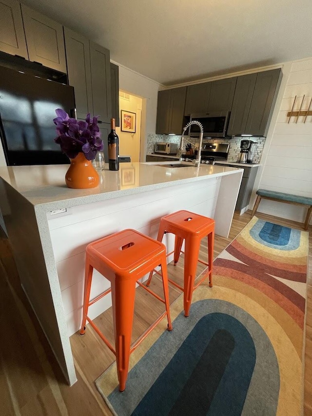 kitchen featuring light countertops, stainless steel microwave, light wood finished floors, and decorative backsplash